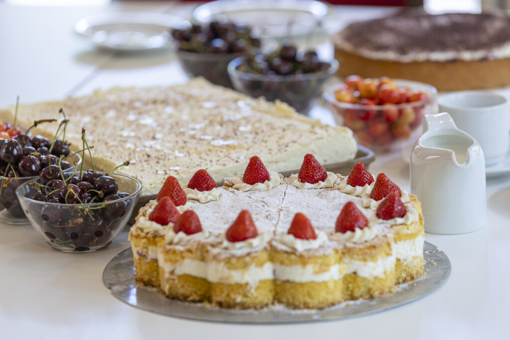Kännchen, Kirschen und verschiedene Kuchen auf einem Kaffeetisch
