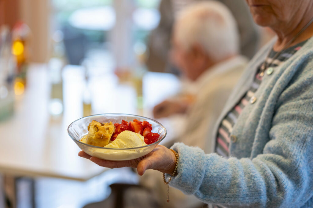 Glasschale mit Desserts wird von einer Frau gereicht